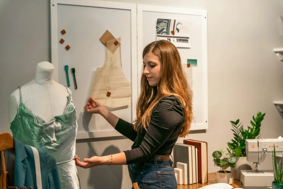 a woman standing in front of a dress on a mannequin
